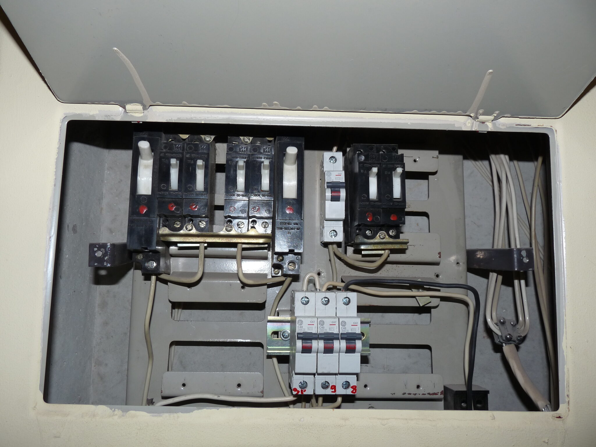 An open electrical panel with multiple circuit breakers and wires.