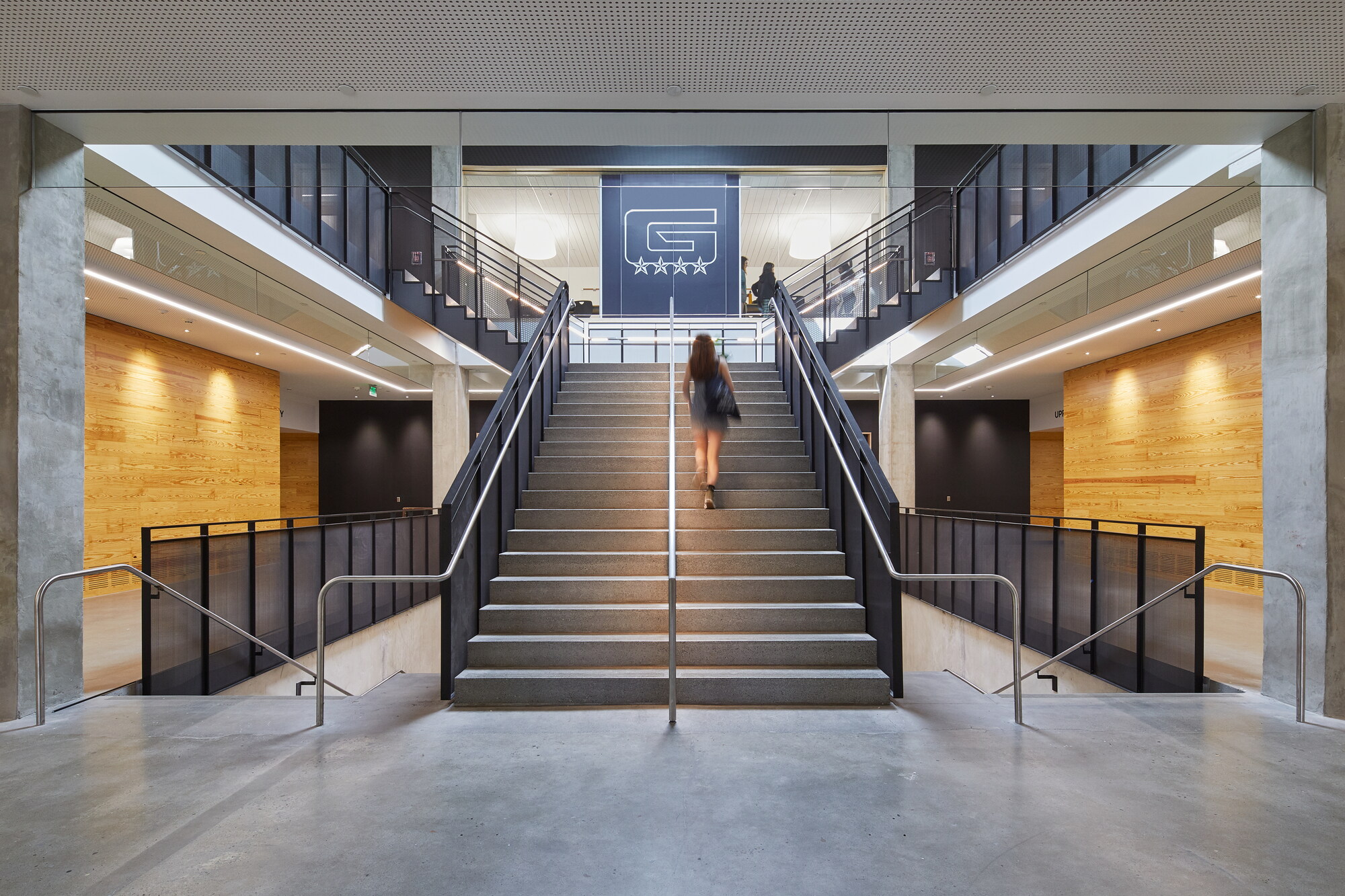 An electrician in Vancouver, WA can enhance modern buildings like Grant High School by expertly installing and maintaining overhead lighting, ensuring safety and functionality, amidst concrete floors and wooden wall panels.