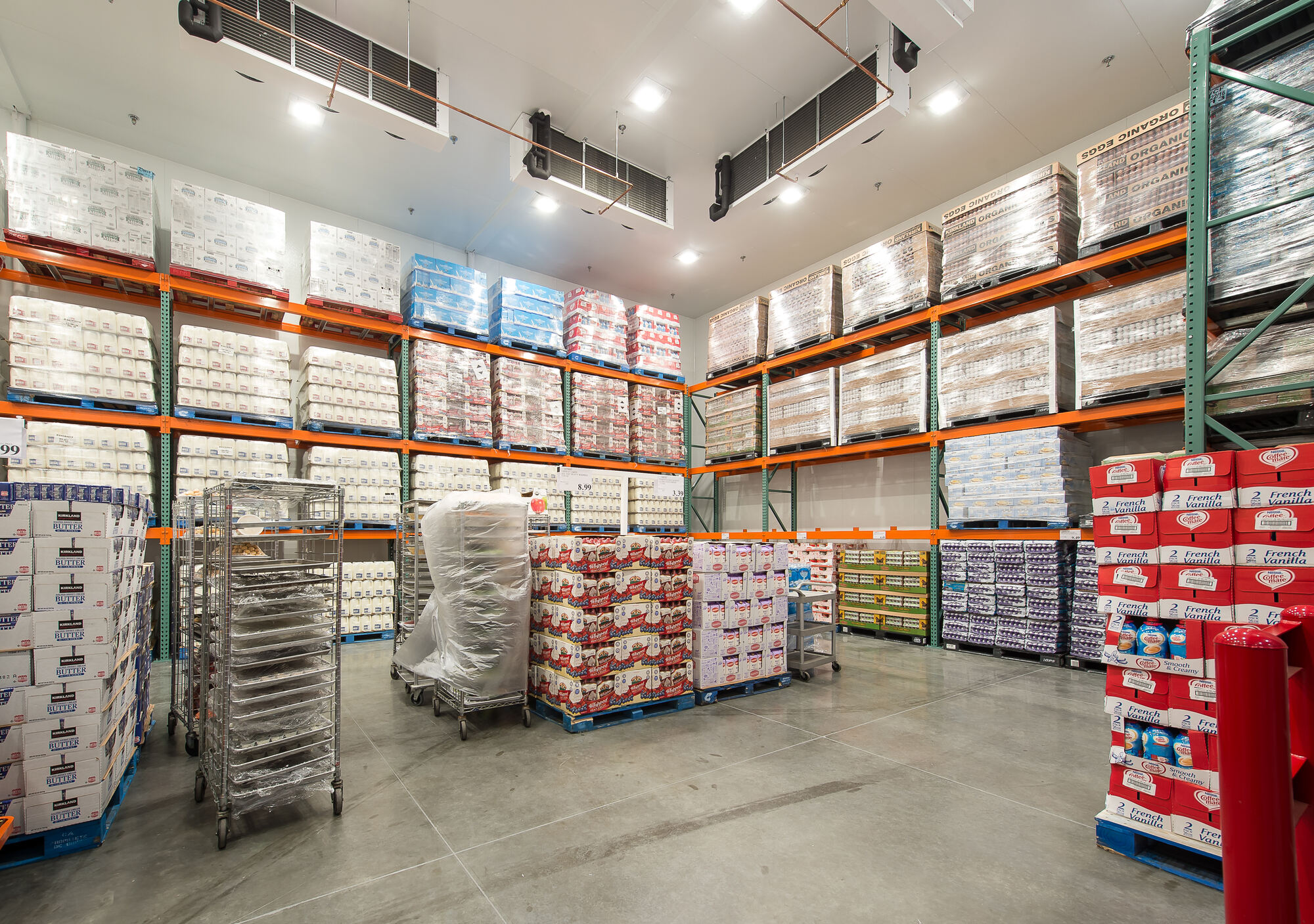 In a large Costco Warehouse, efficient lighting systems illuminate towering shelves storing goods. Aside from a few carts, the polished concrete floor exemplifies effective design. Our electrician services ensure such spaces are optimally lit and functioning safely.