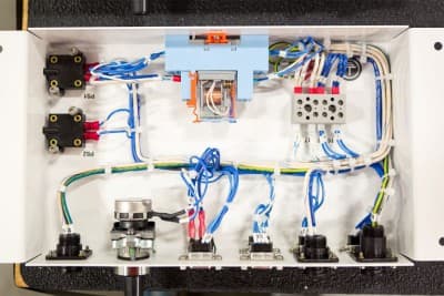 An open electrical panel reveals a complex network of wires, switches, and connectors. Color-coded wires are meticulously organized inside the rectangular metal casing by an electrician in Vancouver, WA.