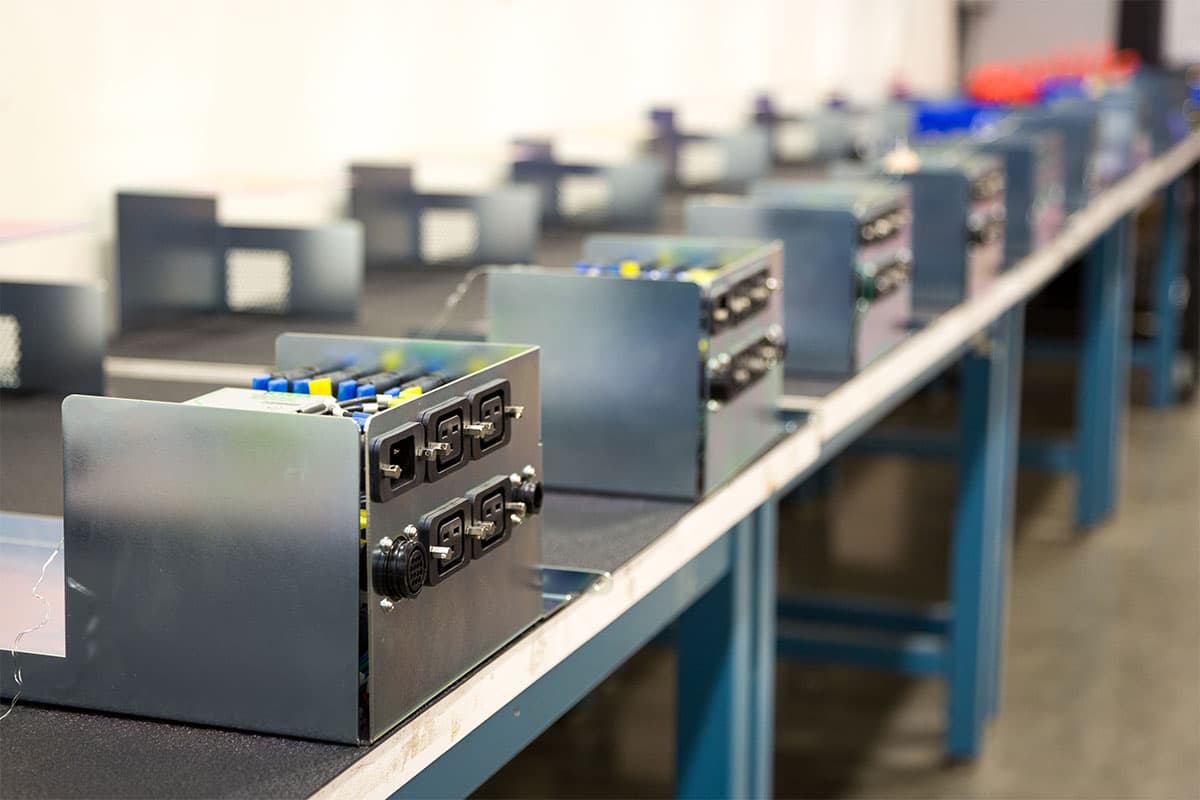 Several electronic devices are lined up on a long factory production line, with partially assembled components visible, showcasing the precision one might expect from an experienced Vancouver electrician.