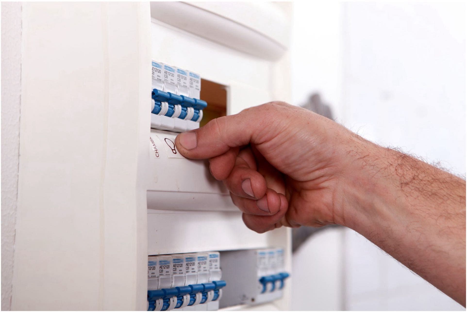A Vancouver electrician flipping a switch in an electrical circuit breaker panel.